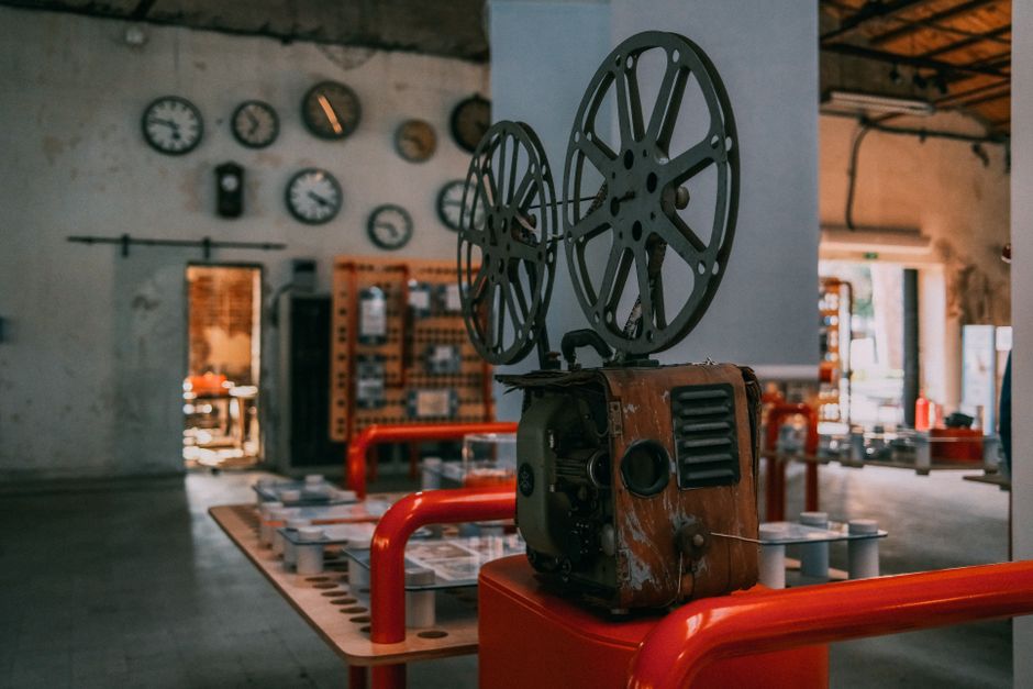 Rustic vintage film projector in an industrial-themed room with wall clocks.